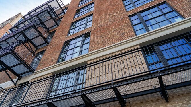 Edifício de apartamentos de tijolo médio com janelas de aluminio e aparência de aço.