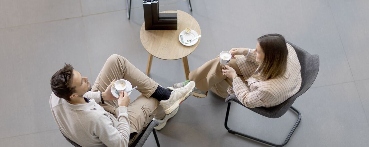 Top vista homem e mulher sentados à mesa bebendo café.