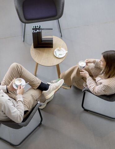Vista superior de homem e mulher sentados em uma mesa, bebendo café.