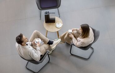 Top vista homem e mulher sentados à mesa bebendo café.